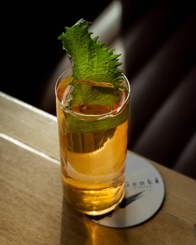 A Hojicha Highball with a large shiso leaf on a Genki coaster