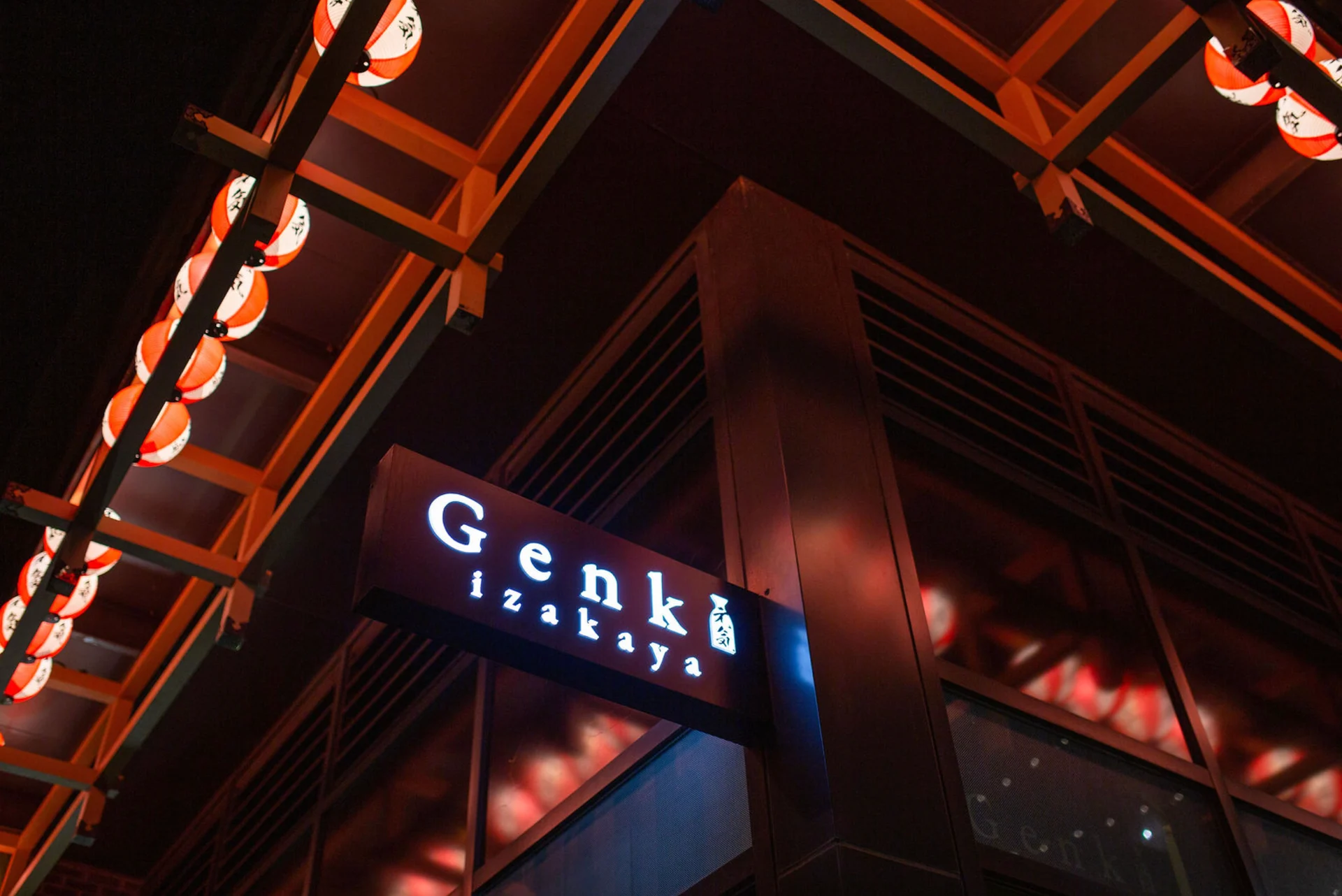 Genki Izakaya’s illuminated sign beneath red lanterns and timber eaves